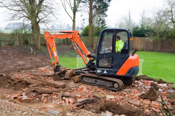 BUCKINGHAM, UK - February 13, 2016. Digger, bulldozer clearing rubble in preparation for hard landscaping a garden in UK